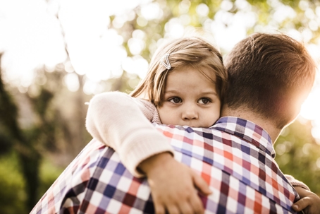 little girl hugging her dad in plaid shirt