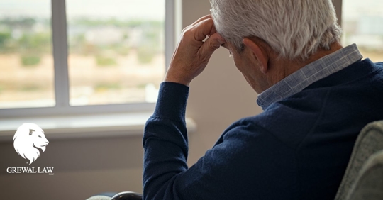 Elder man sitting in front of a window resting his head on his hand.