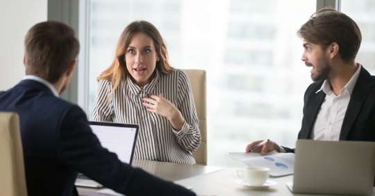 Woman in an office arguing with two male co-workers