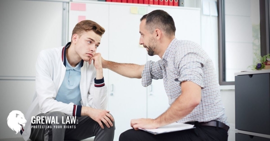 Man with his hand on a teenage boy's shoulder.