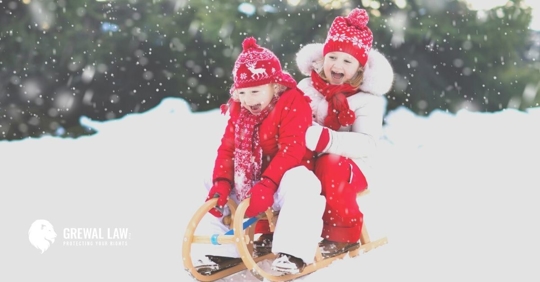 Two happy little girls riding a sled in snow.