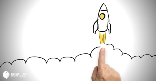 Image of a man's finger pointing to a drawn rocket ship on paper