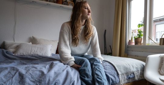 College woman sitting on her bed after being a victim of sexual abuse