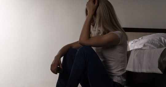 Woman on the side of her bed upset after being sexually attacked